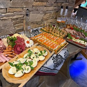 Rustic buffet table with regional cold cuts, bread, and cheeses, set in a cozy mountain-style interior.